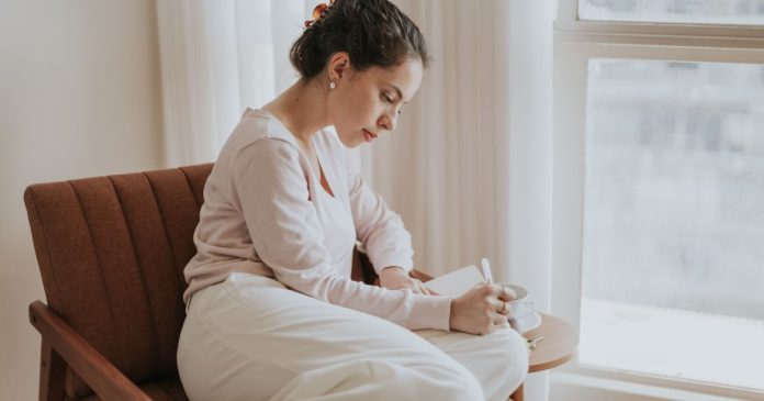 Woman journaling by a window while reflecting on intuition